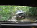 1995 Ford C-350 (Centurion Conversions) - A white pickup truck navigates a wooded trail, its front end angled towards the camera.