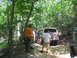 1995 Ford C-350 (Centurion Conversions) - People gather around SUVs on a dirt path surrounded by trees.