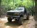 1995 Ford C-350 (Centurion Conversions) - Modified Ford Bronco on a wooded trail with another vehicle in the background.