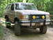 1995 Ford C-350 (Centurion Conversions) - This Ford Bronco is parked on a wooded trail with a bull bar and custom lights.