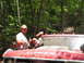 1995 Ford C-350 (Centurion Conversions) - People pose with a red Ford truck in a wooded area, with humorous text on the hood and windshield.