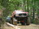 1995 Ford C-350 (Centurion Conversions) - Modified pickup trucks navigate a wooded trail during an off-road event.
