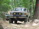 1995 Ford C-350 (Centurion Conversions) - A tan Ford Bronco navigates a challenging rocky trail, custom smiley face lights on the grille guard.
