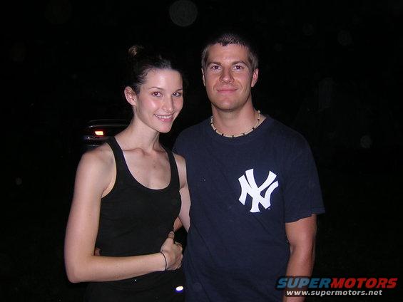 Couple posing at night with a dark car in the background