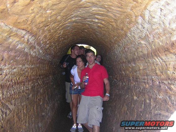 Group of people walking through a rough-hewn tunnel