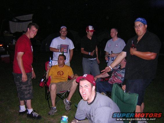 Group of men gathered outdoors at night, some holding drinks