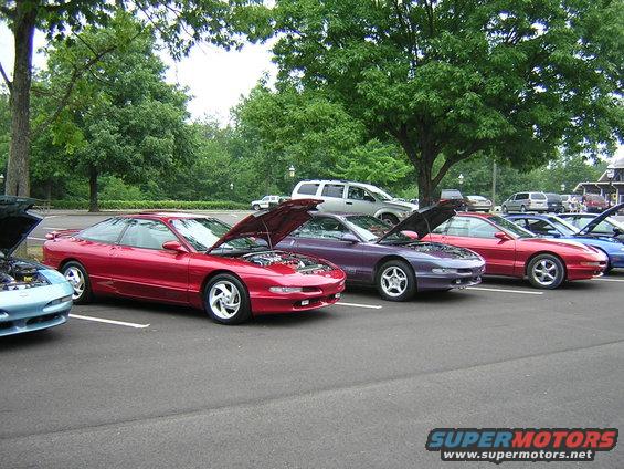 Red 1995 Ford Probe with hood open, parked in a line with other cars