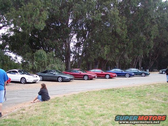 Line of Ford Probe cars parked side-by-side, one white, one dark green, one maroon, one red, one blue, and one dark green