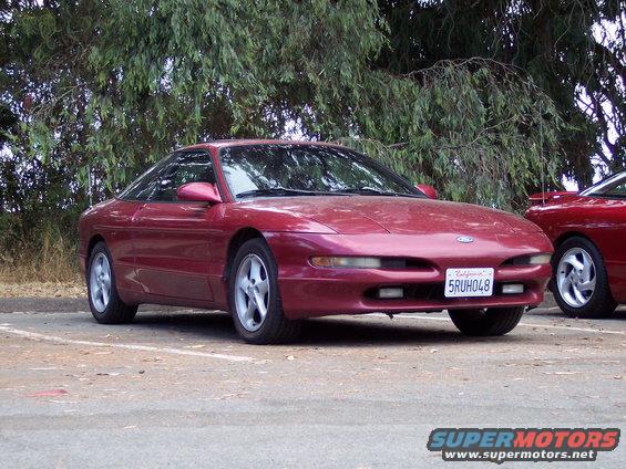 Red 1995 Ford Probe parked outside with another red car to its right