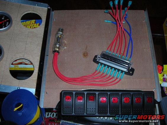 Automotive wiring harness with a fuse box, inline fuse holder, and six toggle switches. Red and blue wires are visible