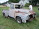 1955 Ford F-100 - This 1955 Ford F-100 pickup truck shows significant rust and wear, sitting in a rural setting.