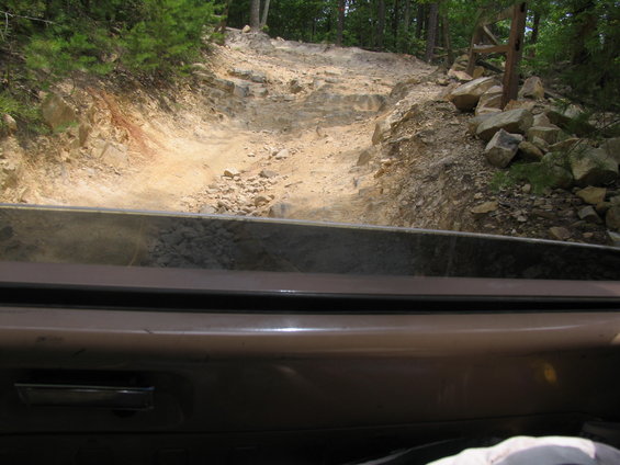 View from inside a vehicle looking out at a rocky, steep off-road trail