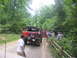 1995 Ford C-350 (Centurion Conversions) - A group of people gather around a modified red off-road vehicle on a wooded dirt path.