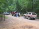 1995 Ford C-350 (Centurion Conversions) - A group of off-road vehicles and people are gathered on a dirt road in a wooded area.