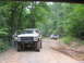 1995 Ford C-350 (Centurion Conversions) - A lifted 1978 Ford Bronco is parked on a dirt road with another truck in the background.
