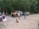 1995 Ford C-350 (Centurion Conversions) - Several people are gathered around a tan Ford Bronco with its hood open in a gravel lot.