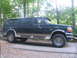 1995 Ford C-350 (Centurion Conversions) - Side view of a dark green 1995 Ford C-350 SUV with tan lower body trim, parked outdoors.