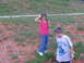 1995 Ford C-350 (Centurion Conversions) - Two children are in a grassy area with dirt patches. The girl waves while the boy looks down.