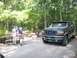 1995 Ford C-350 (Centurion Conversions) - Two people stand by a picnic table near a green Ford Bronco in a wooded campground.