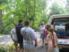 1995 Ford C-350 (Centurion Conversions) - People are gathered around the open tailgate of a tan pickup truck in a wooded area.