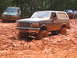 1995 Ford C-350 (Centurion Conversions) - Multiple off-road vehicles navigate a muddy terrain, with one Ford Bronco deeply mired.