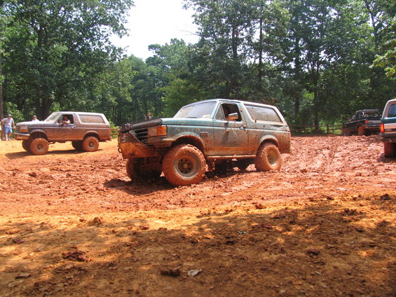 Muddy Ford Bronco and other off-road vehicles on a dirt track