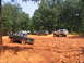 1995 Ford C-350 (Centurion Conversions) - Several off-road vehicles are gathered in a muddy clearing surrounded by trees.