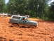 1995 Ford C-350 (Centurion Conversions) - A green SUV navigates a challenging mud pit, with other vehicles and spectators in the background.