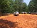 1995 Ford C-350 (Centurion Conversions) - Multiple off-road vehicles are gathered on a muddy hill during an event.