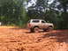 1995 Ford C-350 (Centurion Conversions) - A tan Ford Bronco navigates a muddy terrain, its lifted suspension and off-road tires clearly visible.