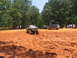 1995 Ford C-350 (Centurion Conversions) - Several off-road vehicles are navigating a muddy terrain with spectators observing from a distance.