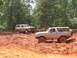 1995 Ford C-350 (Centurion Conversions) - Two Ford Broncos navigate a challenging muddy terrain during an off-road event.