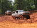 1995 Ford C-350 (Centurion Conversions) - Two SUVs navigate a muddy off-road course during an event in July 2006.