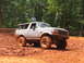 1995 Ford C-350 (Centurion Conversions) - White 1995 Ford Bronco navigating a muddy off-road trail.