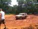 1995 Ford C-350 (Centurion Conversions) - A tan and white Ford Bronco navigates through thick mud during an off-road event, with another vehicle visible in the background.