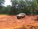 1995 Ford C-350 (Centurion Conversions) - Two SUVs navigate a muddy off-road course surrounded by trees.