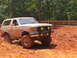 1995 Ford C-350 (Centurion Conversions) - Tan Ford Bronco with off-road tires kicks up mud while navigating a dirt track.