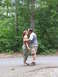 1995 Ford C-350 (Centurion Conversions) - Couple shares a kiss on a path in a wooded area.