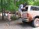 1995 Ford C-350 (Centurion Conversions) - A man loads gear into a mud-covered Ford Bronco, with another off-road vehicle visible in the background.