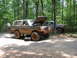 1995 Ford C-350 (Centurion Conversions) - Two off-road vehicles, a Ford Bronco and a Ford truck, are parked on a dirt road in a wooded area.