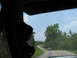 1995 Ford C-350 (Centurion Conversions) - A tan pickup truck travels down a rural, tree-lined road on a sunny day.