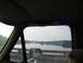 1995 Ford C-350 (Centurion Conversions) - View from inside a vehicle, showing a river and landscape through the window, with a side mirror reflecting the road.