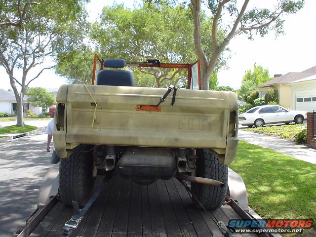 Rear view of a tan 1977 Ford Bronco on a trailer, with 'FORD' visible on the tailgate