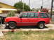 1992 Ford Explorer - A red SUV is parked on a driveway in front of a yellow house.