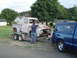 1955 Ford F-100 - A man inspects a weathered 1955 Ford F-100 pickup truck being transported on a trailer.