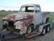 1955 Ford F-100 - A rusty 1953 Ford F-100 truck is transported on a U-Haul trailer, its front end partially dismantled.