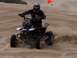 1999 Yamaha WARRIOR - A rider on a black ATV navigates sand dunes, kicking up dust as they go.