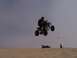 1999 Yamaha WARRIOR - A quad bike rider catches air over sand dunes while two spectators watch from below.