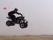 1999 Yamaha WARRIOR - A rider on a quad bike catches air over a sandy terrain under a hazy sky.