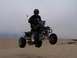 1999 Yamaha WARRIOR - Rider jumps a quad bike over sand dunes under an overcast sky.